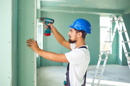 建筑工人在建筑工地安装石膏板干墙