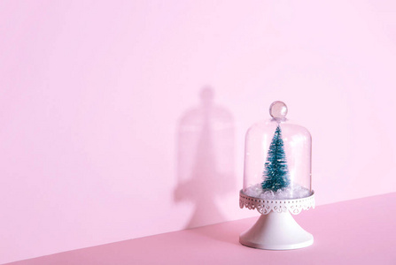 创意圣诞设计在粉红色粉彩背景与圣诞树。