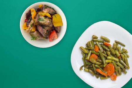  Green beans with garlic carrots on a white plate on a colored b