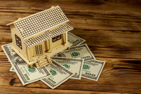 木制背景的房子模型和一百美元的。房地产投资住房贷款住房抵押贷款房地产概念