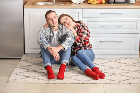 快乐的年轻夫妇坐在厨房的地板上