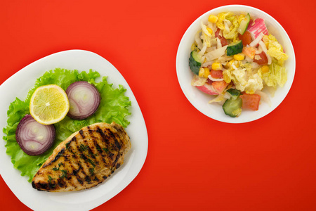  grilled chicken with vegetables lemon, salad, onion on a color