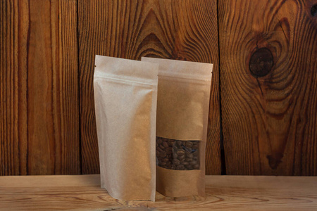 棕色牛皮纸袋，咖啡豆正面，木质背景。食品和货物的包装。