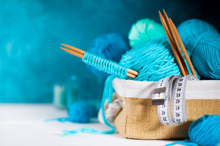 篮子里编织用的蓝色和水蓝色纱线。针织针