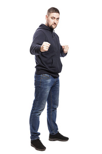 A young man in jeans in a fighting stance. Full height. Isolated