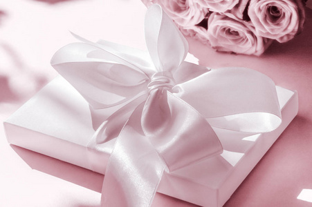 Luxury holiday silk gift box and bouquet of roses on blush pink 