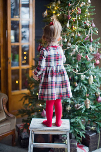 快乐的小女孩穿着裙子装饰圣诞树