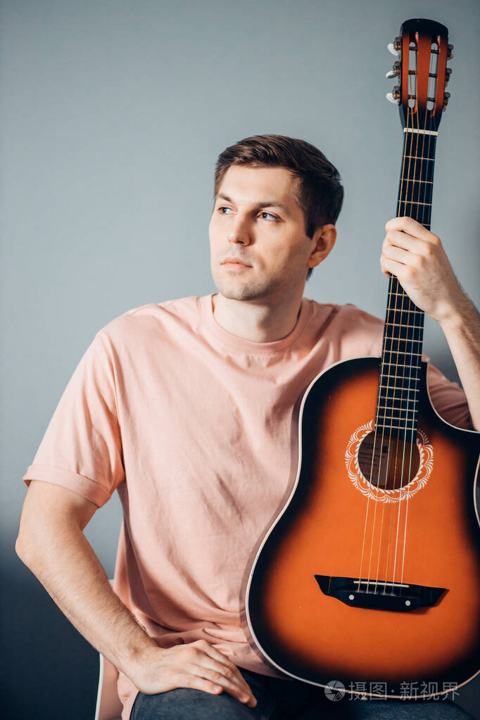 年轻漂亮的白人男子与吉他单独摆姿势的肖像