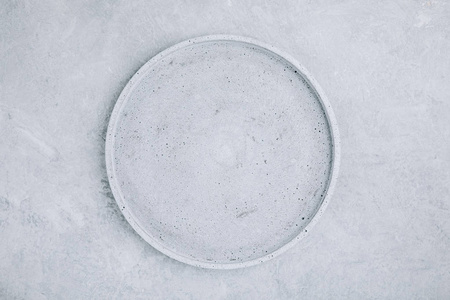 Empty round stone plate on gray concrete background, top view