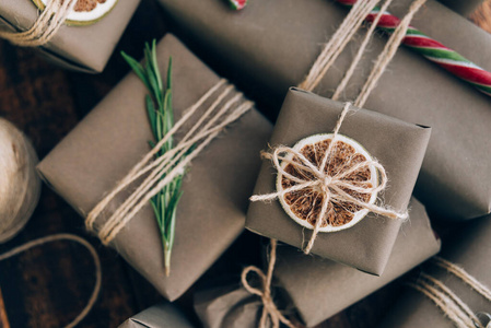 礼物和礼物用手工纸包装，棕色木质背景上有装饰。假日零浪费理念。