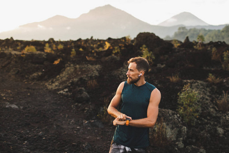 Young hipster runner with beard using smart watch and listening 