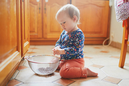 女婴坐在厨房的地板上玩厨具图片