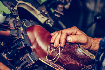 Experienced shoemaker using a special machine for putting shoes 