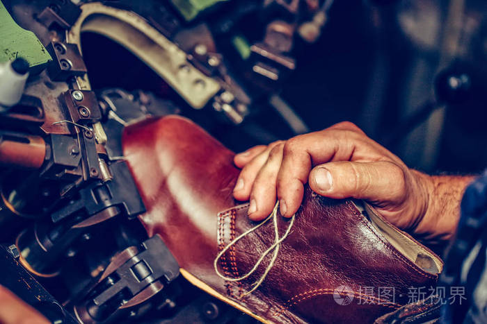 Experienced shoemaker using a special machine for putting shoes 