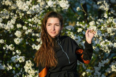 girl on the background of a blossoming apple tree. in black clot