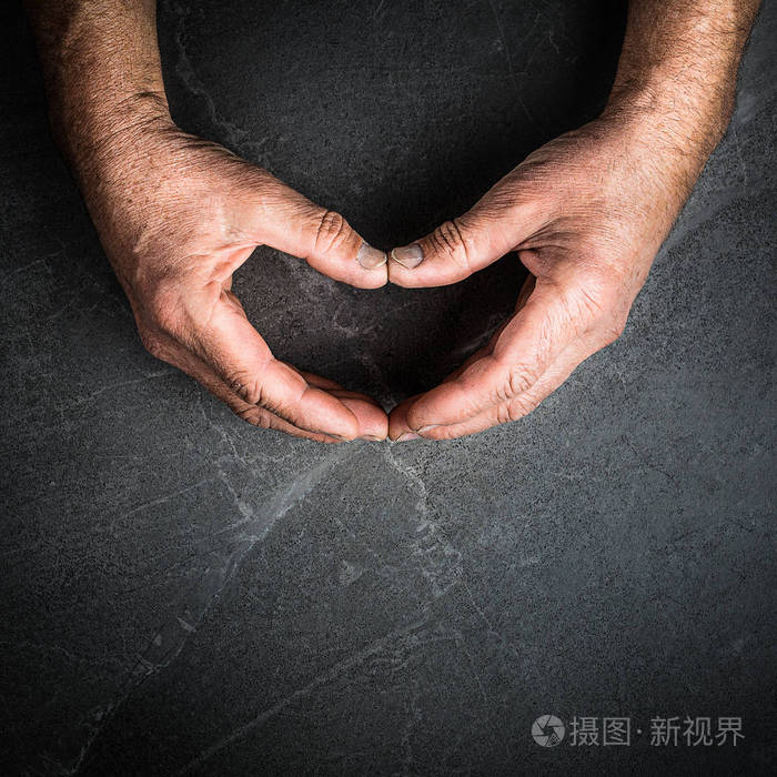 双手握着灰色背景上的心形图案