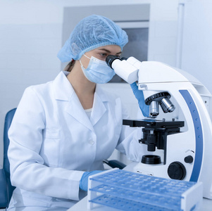 实验室工作人员在面罩和手套上使用现代显微镜