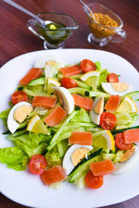 白盘蔬菜沙拉。新鲜沙拉鸡蛋，西红柿，菠菜和鳄梨在白色木质背景俯视图。健康食品。