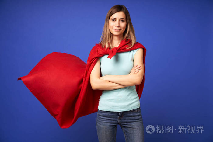 穿着红色超级英雄斗篷的女人站在空荡荡的蓝色背景上