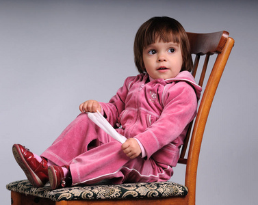 穿着粉红色衣服的小女孩坐在椅子上