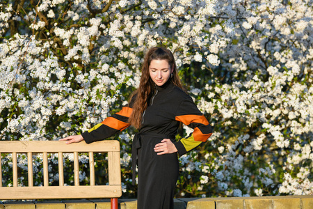 girl on the background of a blossoming apple tree. in black clot