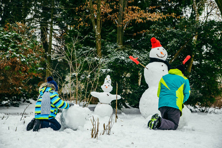 可爱的小男孩在堆雪人。滚大雪球