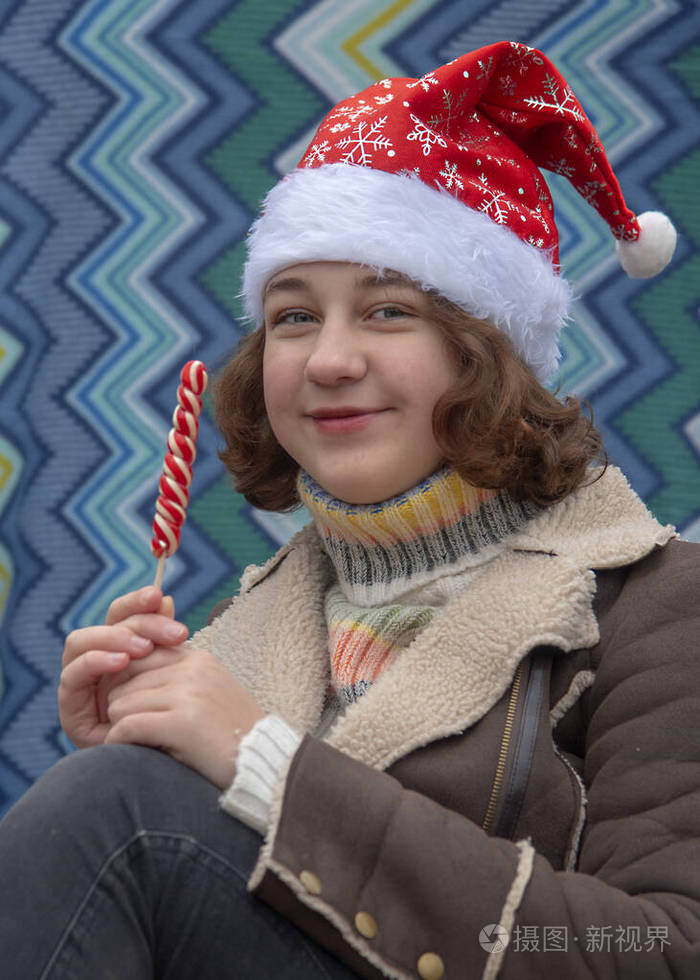 一个戴着圣诞老人帽的少女，手里拿着鲜艳的棒棒糖