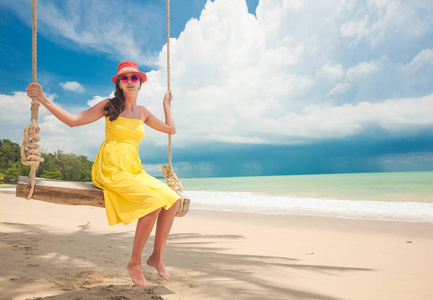 一位美丽的女人在可可岛的热带海滩上荡秋千。泰国亚洲