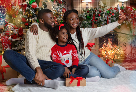 快乐的黑人妇女与丈夫和女儿一起拍圣诞自拍