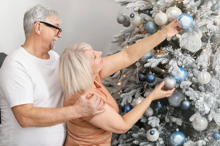 幸福的成熟夫妇在家装饰圣诞树
