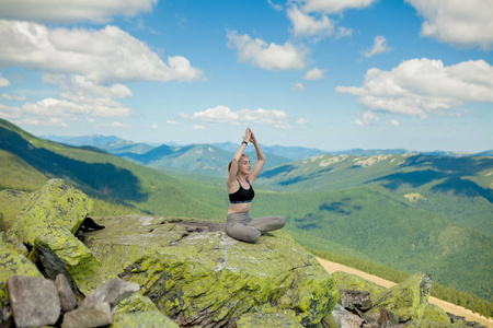 在山顶做瑜伽练习莲花姿势的女孩。