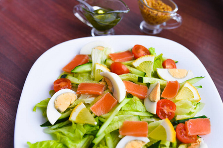 白盘蔬菜沙拉。新鲜沙拉鸡蛋，西红柿，菠菜和鳄梨在白色木质背景俯视图。健康食品。