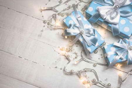 白色木质背景的蓝色礼品盒和珍珠灯