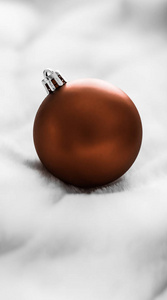 Chocolate brown Christmas baubles on white fluffy fur backdrop, 