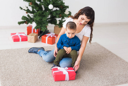 圣诞节，单亲家庭和假日概念可爱的小男孩拿着圣诞礼物给他的母亲在家。