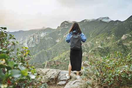 背着背包的年轻女游客在山顶上放松，欣赏山谷的景色