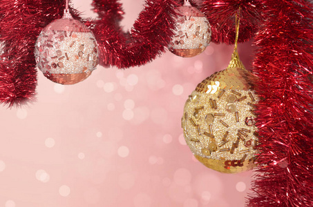 Christmas balls on a tinsel garland on a background in pink and 