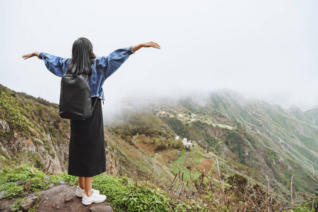 背着背包的年轻女游客在山顶上放松，欣赏山谷的景色