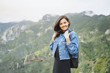 快乐微笑的女人背着背包在山上。旅游和生活方式概念