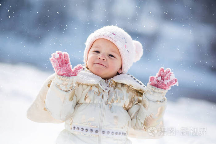 穿着白夹克的小女孩玩得很开心，在外面玩，被雪包围着。