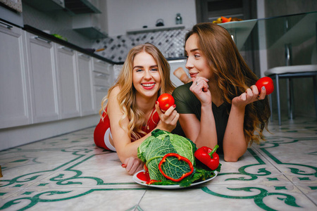 两个体育女孩在厨房里吃蔬菜