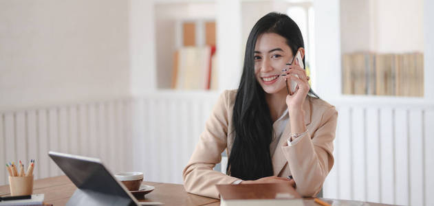 Portrait of young businesswoman speaking on the phone with custo