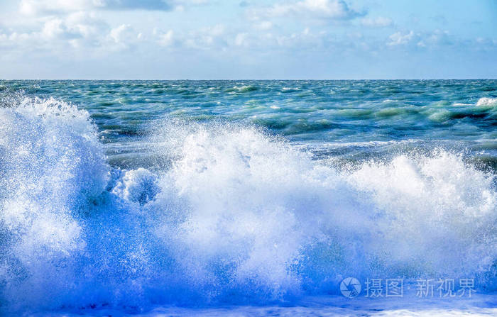 海浪拍打在波涛汹涌的海滩上的白色浪花