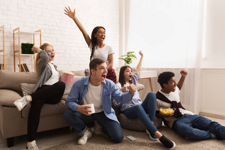 Emotional football fans. Teens watching match at home