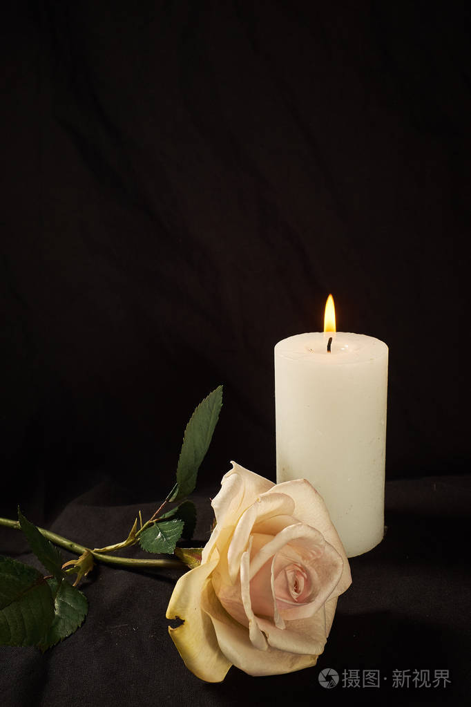 在黑色背景上点燃蜡烛和一朵美丽的玫瑰