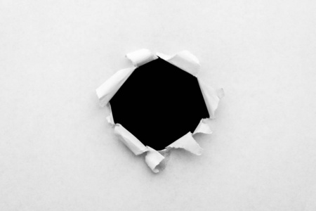白纸上的圆孔，边缘被撕破，里面有一个黑色的孤立的背景。