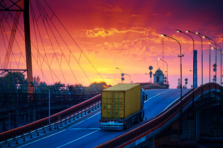 卡车载着集装箱在桥上驰骋，美丽的夕阳，货车在工业海港，公路就往上走