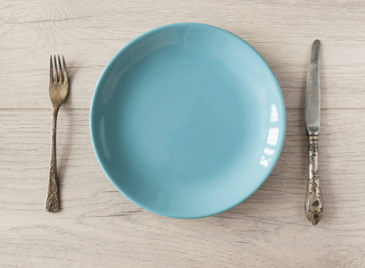 Empty blue plate with a copy space for food with fork and knife 