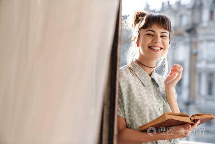 可爱的年轻漂亮的女人在阳台上看书