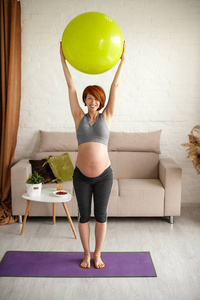 一位年轻漂亮的孕妇的画像。在家里和fitball一起练习。